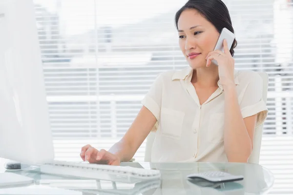 Businesswoman using cellphone and computer at desk — Stock Photo, Image