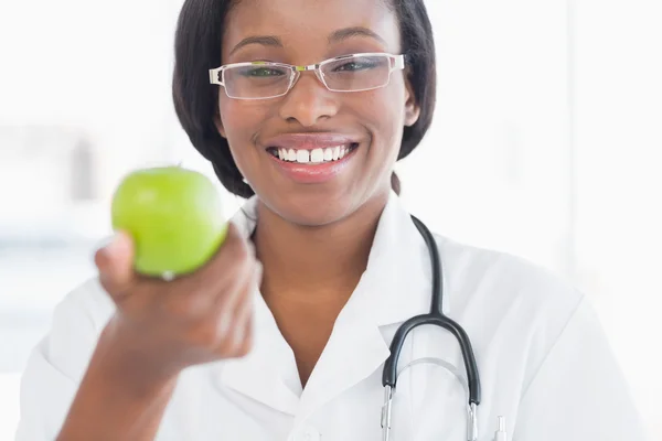 Portrait of a smiling female doctor holding an apple — Stock Photo, Image