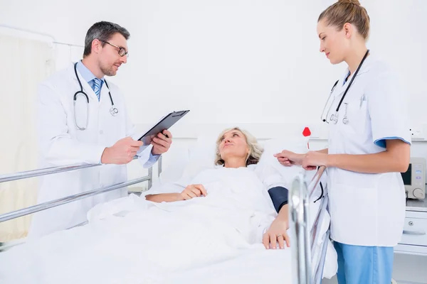 Médicos visitando a una paciente femenina en el hospital —  Fotos de Stock