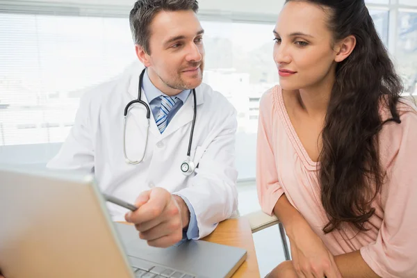 Doctor showing something on laptop to patient in medical office — Stock Photo, Image