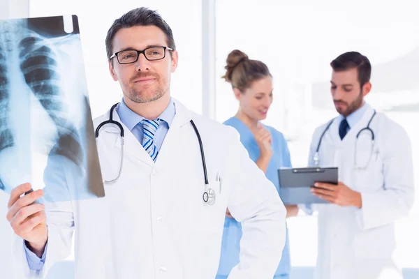 Médico masculino examinando rayos X con colegas detrás — Foto de Stock