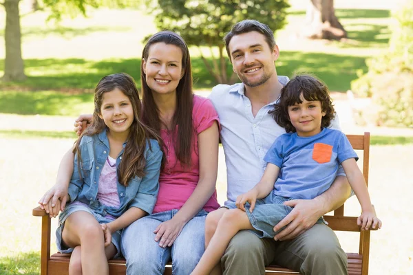 Couple with young kids sitting on park bench — Stock Photo, Image