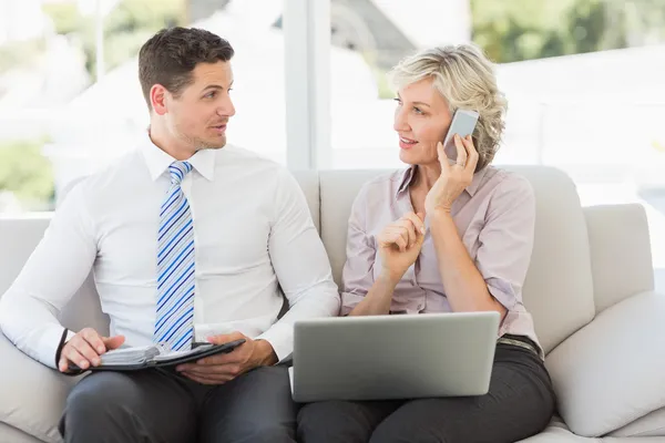 Zakenman en zijn secretaresse met mobiel en laptop thuis — Stockfoto