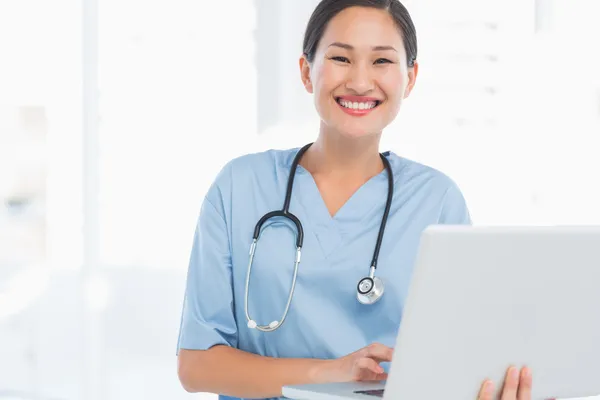 Cirurgiã sorridente usando um laptop — Fotografia de Stock