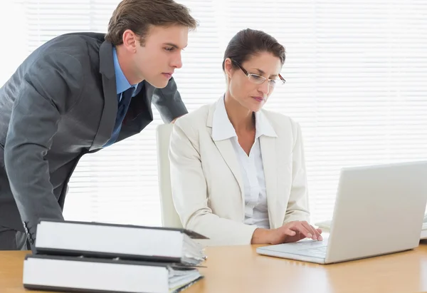 Business couple using laptop at office desk — Stock Photo, Image