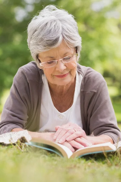 Seniorin liest im Park ein Buch — Stockfoto