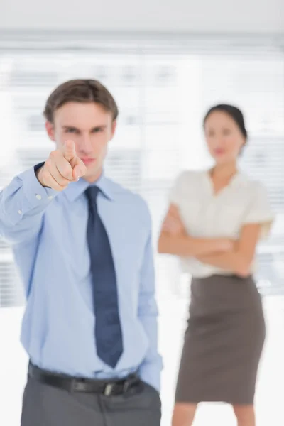 Businessman pointing towards camera with woman in office — Stock Photo, Image