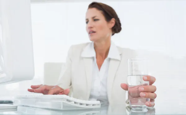 Empresaria usando computadora mientras sostiene un vaso de agua —  Fotos de Stock