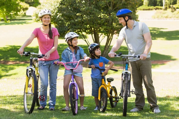 Familj på fyra med cyklar i parken — Stockfoto