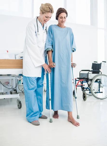 Doctor helping patient in crutches at the hospital — Stock Photo, Image