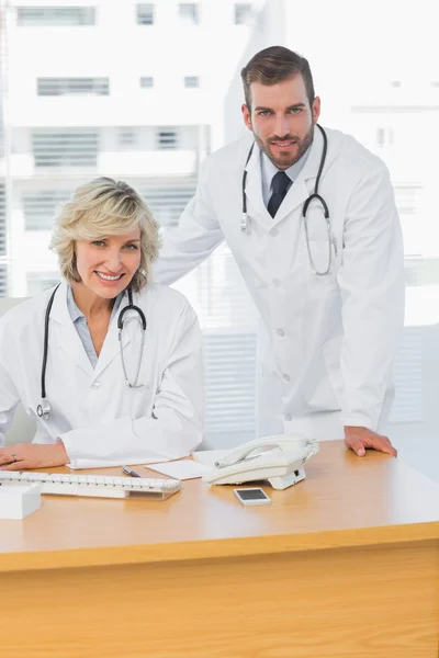 Médicos sonrientes con computadora en el consultorio médico —  Fotos de Stock