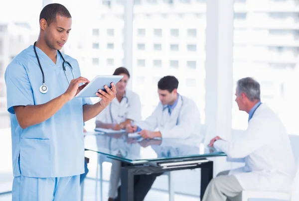 Chirurg pomocí digitálních tabletu se skupinou kolem stolu v nemocnici — Stock fotografie