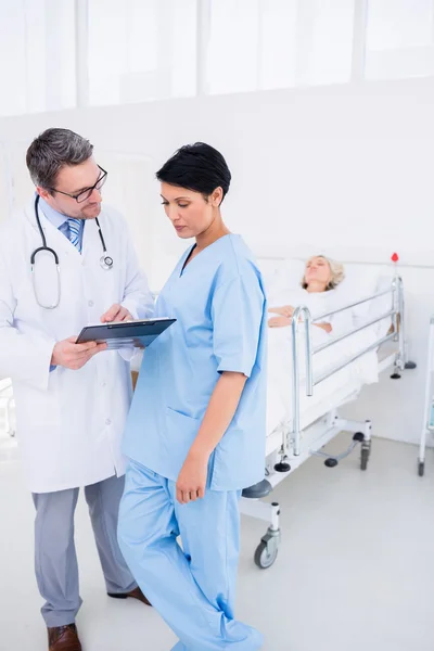 Artsen verslagen bespreken met patiënt in het ziekenhuis — Stockfoto