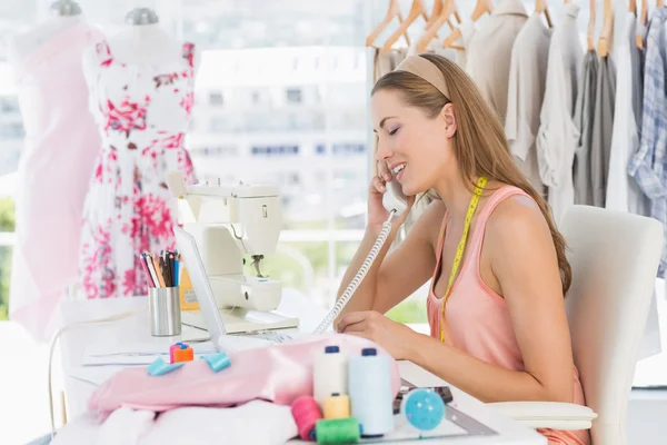 Jonge vrouwelijke modeontwerper met behulp van telefoon in studio — Stockfoto