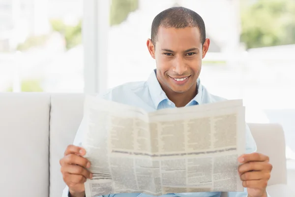 Empresário sorridente lendo jornal no sofá — Fotografia de Stock