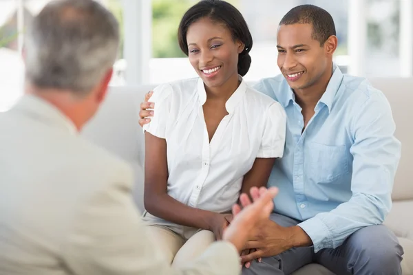 Junges Paar hört Verkäufer auf der Couch zu — Stockfoto