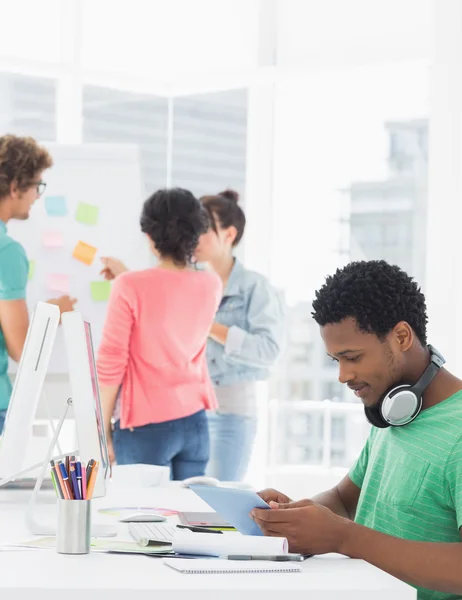 Casual man met digitale tablet met collega's achter in office — Stockfoto