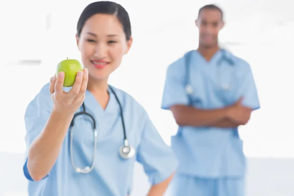 Kobieta chirurg trzyma jabłko z kolega w szpitalu — Zdjęcie stockowe