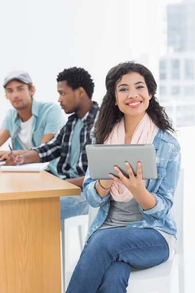 Femme souriante utilisant une tablette numérique avec des collègues derrière dans off — Photo