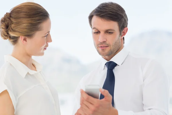 Snyggt klädd kollegor tittar på mobiltelefon — Stockfoto