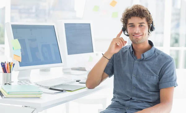 Homem casual com fone de ouvido sentado por computadores no escritório — Fotografia de Stock