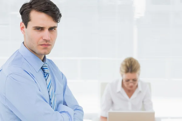 Homme d'affaires sérieux avec une femme travaillant derrière au bureau — Photo