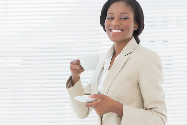 Elegancka kobieta uśmiechający się przy filiżance herbaty w biurze — Zdjęcie stockowe
