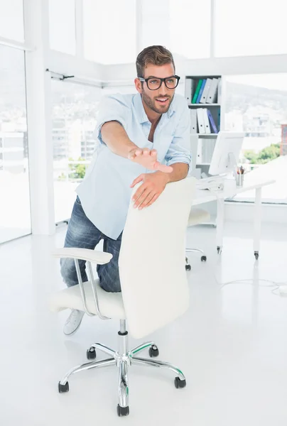 Gelukkig jonge man geknield op stoel in office — Stockfoto