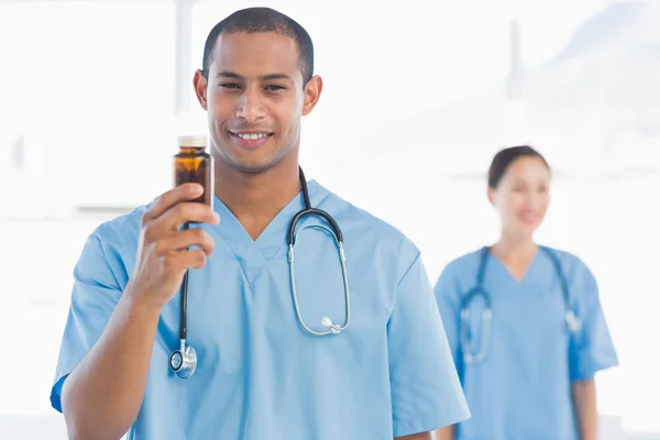 Médico sonriente sosteniendo una botella de pastillas con su colega —  Fotos de Stock