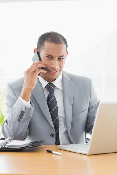 Lachende zakenman met behulp van laptop en mobiele telefoon — Stockfoto