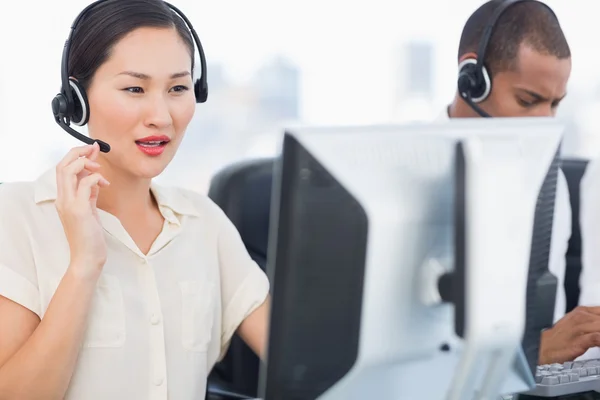 Colegas con auriculares que usan computadoras en la oficina —  Fotos de Stock