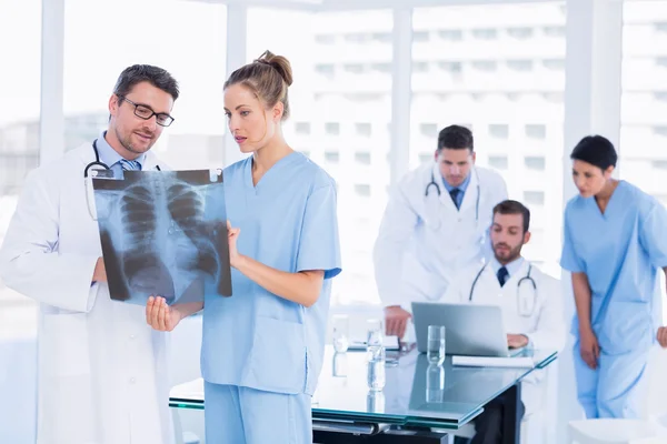 Artsen x-ray onderzoek met collega's met behulp van laptop achter — Stockfoto