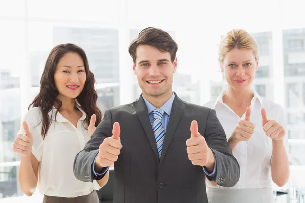 Smiling businessman giving thumbs up with his team Royalty Free Stock Images