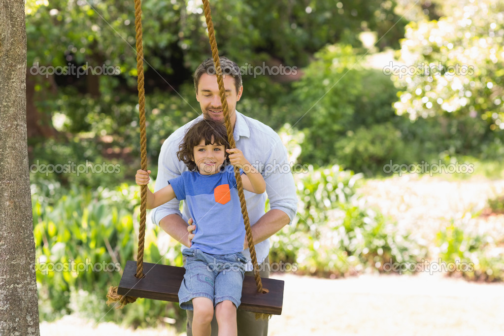 Happy Father Pushing Boy On Swing Stock Photo By C Wavebreakmedia