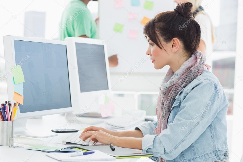 Artist using computer with colleagues behind at office Stock Photo by  ©Wavebreakmedia 39197341