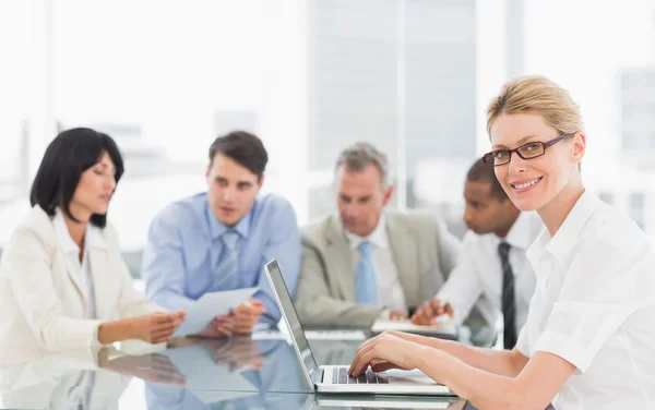 Geschäftsfrau benutzt ihren Laptop während einer Besprechung beim Anblick eines Kameramanns — Stockfoto