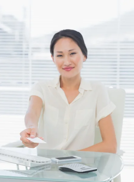 Woman handing over her business card at desk — Stock Photo, Image