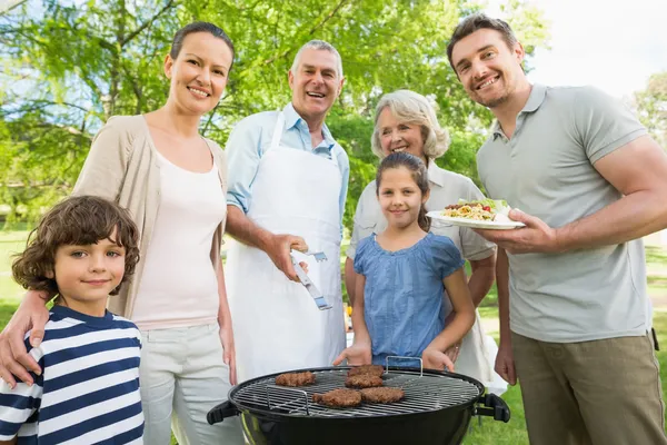 Extended family standing at barbecuing in park — Stock Photo, Image