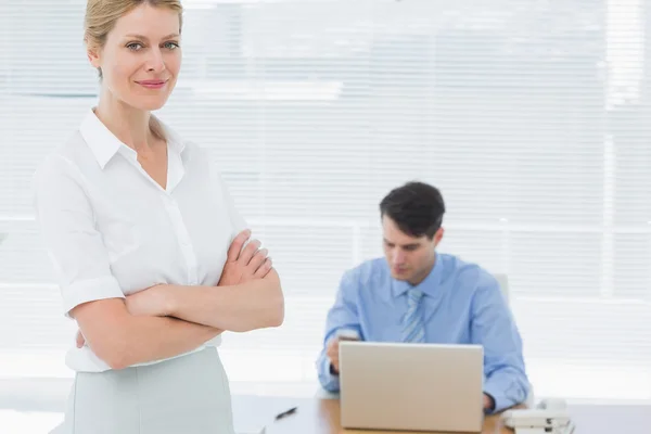 Mujer de negocios sonriente con el hombre trabajando detrás en la oficina —  Fotos de Stock