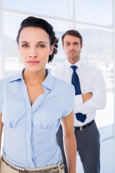 Serious businesswoman with male colleague in background — Stock Photo, Image