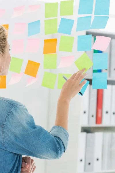 Vista trasera de una artista femenina mirando coloridas notas adhesivas —  Fotos de Stock