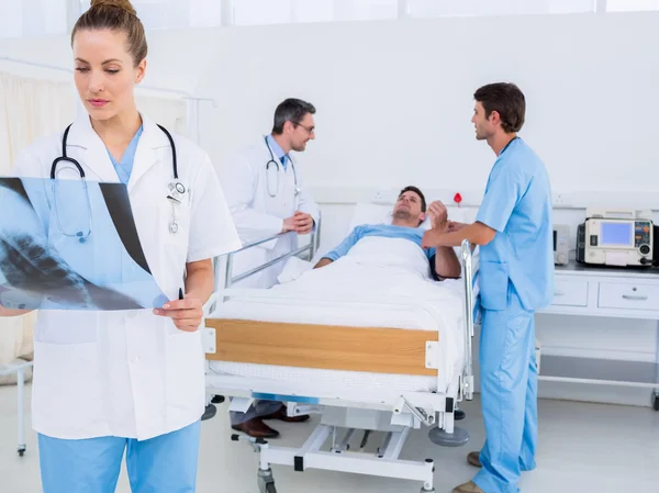 Doctor examining x-ray with colleagues and patient in hospital — Stock Photo, Image