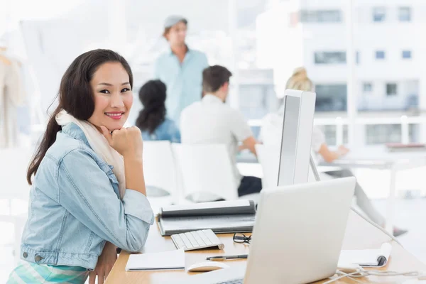 Casual young woman with colleagues behind in office — Stock Photo, Image