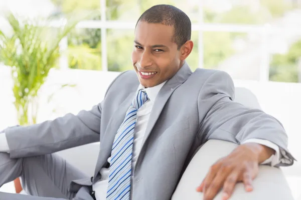 Empresário sentado no sofá sorrindo para a câmera — Fotografia de Stock