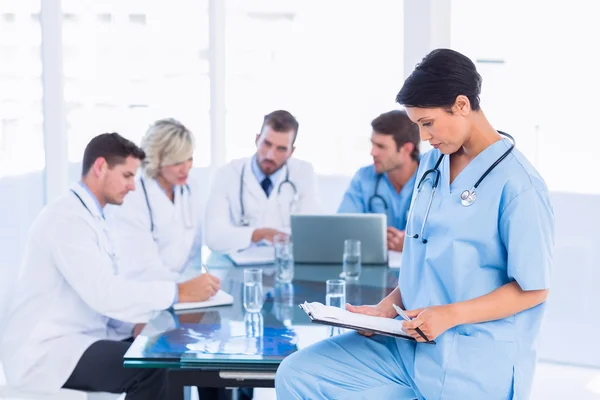 Female surgeon looking at reports with colleagues in meeting — Stock Photo, Image