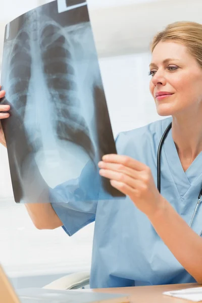 Cirujano estudiando una radiografía sentada en su escritorio — Foto de Stock