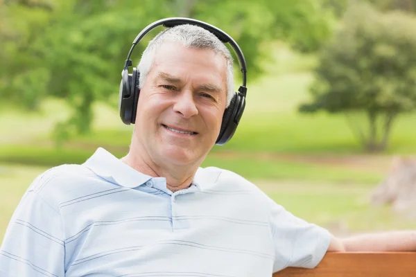 戴着耳机在公园的高级男人微笑着 — 图库照片