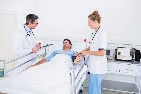 Médicos visitando um paciente do sexo masculino no hospital — Fotografia de Stock
