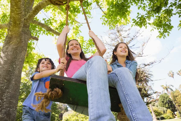 Bambini spingendo la madre sull'altalena — Foto Stock