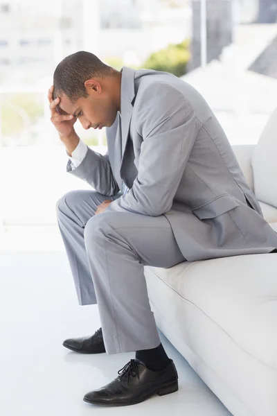 Worried businessman sitting on couch with head in hand — Stock Photo, Image